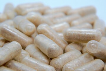 Beige oval pills, tablets. Medicines on the white background. Pile of pills, capsules. Addiction to drugs and supplements. Medical and healthcare concept. 