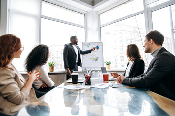 African american confident businessman making presentation on conference, talking about financial graphs. Stylish male employee submit work report on briefing meeting