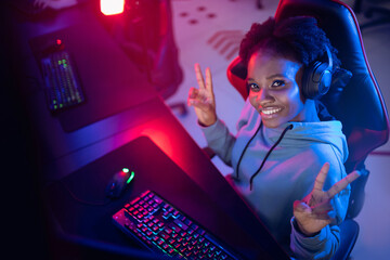 Happy Streamer African young woman professional cyber gamer online video games computer, dark color © Parilov