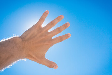 The guy stretched his hand forward towards the blue sky and the sun. The concept of freedom