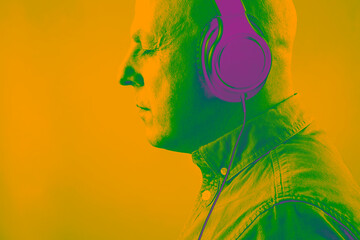 portrait of a man in acid bright color with headphones in relaxation listening to music