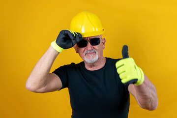 worker with gloves and helmet showing thumb up against yellow background