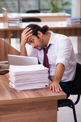 Obraz premium Young male employee and too many work in the office