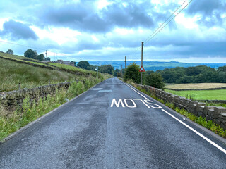 View down, Varley Road, with dry stone walls, fields and distant hills in, Slaithwaite, Huddersfield, UK