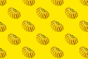 Pattern of small ripe yellow bananas on bright yellow background. Fruit background summer tropical pattern