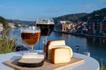 Glass of Belgian abbey beer and tasting of cheeses made with trappist beer and fine herbs with view on Maas river in Dinant, Wallonia, Belgium