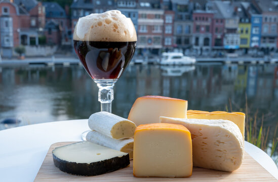 Glass of Belgian abbey beer and tasting of cheeses made with trappist beer and fine herbs with view on Maas river in Dinant, Wallonia, Belgium