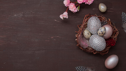 Fototapeta na wymiar Flat lay Easter nest and eggs on brown bakcground with pink blossom flowers copy space