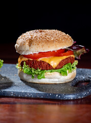 Tasty vegetarian food, homemade cheeseburgers made from plant based soya meat with cheese, onion, green lettuce and tomatoes