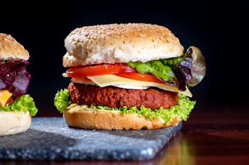 Tasty vegetarian food, homemade cheeseburgers made from plant based soya meat with cheese, onion, green lettuce and tomatoes