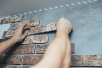 Professional builder gluing decorative brick on wall