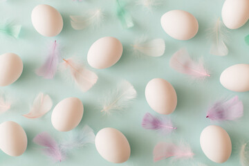 White Easter eggs and feathers on pastel blue background. Top view, flat lay