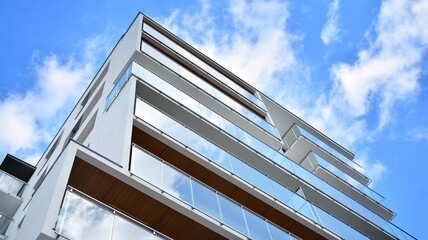 Futuristic square architecture of apartment building. Real estate with panoramic windows and blue sky with clouds.