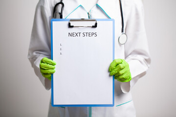 Doctor in a white coat holds a letter with text next steps