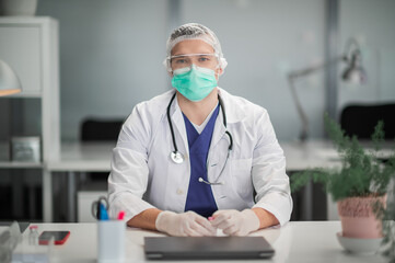 A young therapist in a polyclinic sits at his desk and shows a new coronavirus vaccine.