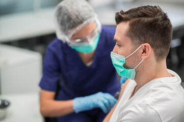 In the laboratory at the hospital, a nurse gives an injection into the arm of a male patient.