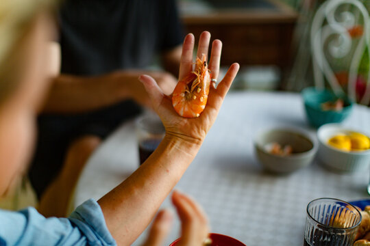 A person holding a large shrimp in their hand, using it as a reference to show the shrimp’s impressive size