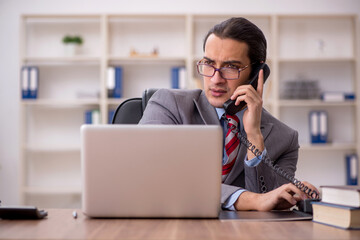 Fototapeta premium Young male employee sitting at workplace