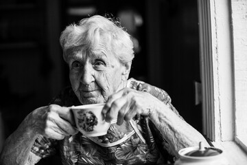 An old woman sitting at the table. Black and white photo.