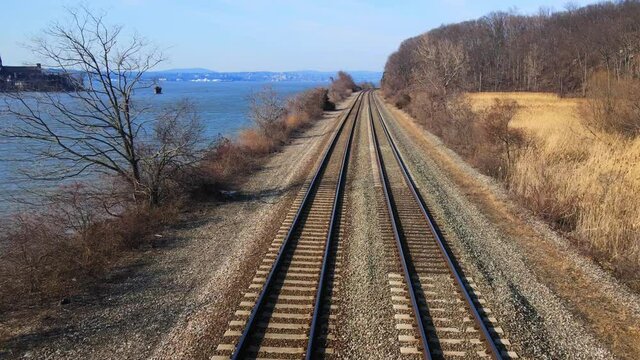 Aerial Drone Footage Down Railroad Train Tracks In A River Valley With Water In Early Spring. This Is The Amtrak Hudson Line In New York In The Hudson Valley