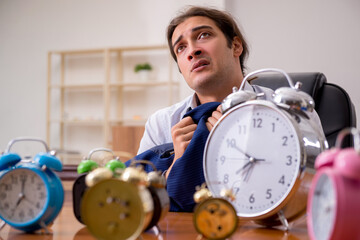 Young male employee sleeping in the office in time management co