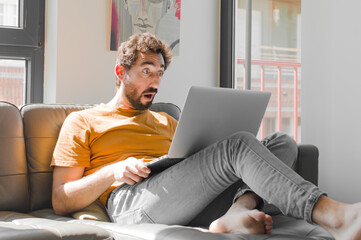 young bearded man looking very shocked or surprised, staring with open mouth saying wow with a...