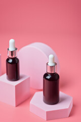 Serum in brown glass bottles with a pipette on a light pink background on pink podiums, mockup