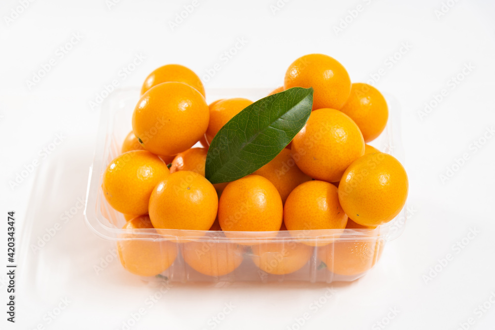 Wall mural a box of kumquat with a green leaf isolated on white background, seasonal fruit