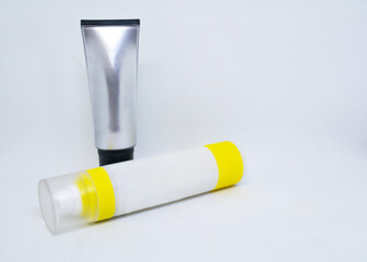 Standing plastic gray-silver tube and lying white-pastel yellow. Jars of the beauty industry. For taking care of body, face, skin