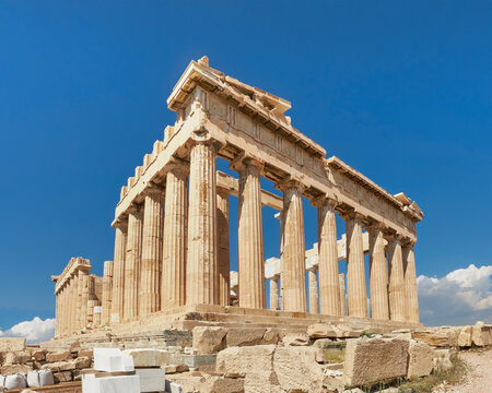 Acropolis, ancient Greek fortress in Athens, Greece. Panoramic image of Parthenon temple on a bright day with blue sky and faraway clouds. Classical Greek heritage