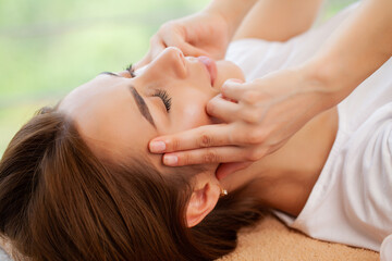 Obraz na płótnie Canvas Young pretty woman enjoying face massage procedure