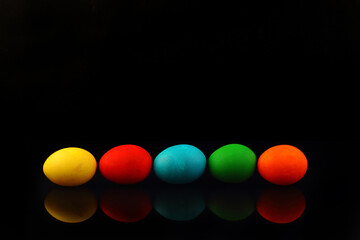 Top view a line of multicolored eggs on a black isolated background. Happy Easter card. Dyed Easter eggs. Copy space for your text. Flat lay style. Top view.