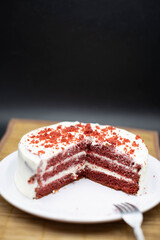 Red velvet cake, classic three layered cake from red butter sponge cakes with cream cheese frosting, American cuisine, white plate, bamboo coat