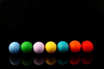 Top view a line of multicolored eggs on a black isolated background. Happy Easter card. Dyed Easter eggs. Copy space for your text. Flat lay style. Top view.