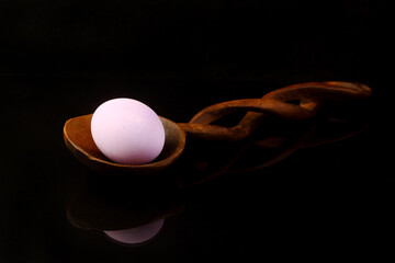 Easter egg  on a wooden spoon on black background with space for copy