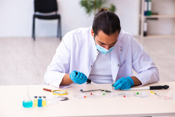 Young male chemist working in the lab during pandemic