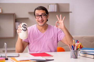 Young male student holding moneybag at home