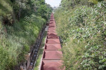 Obraz premium Vista de trem de carga da MRS em movimento na cidade com containers carregado de minério de ferro.