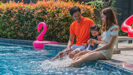 family dad mom and kid having fun together playing by swimming pool in resort and hotel on vacation