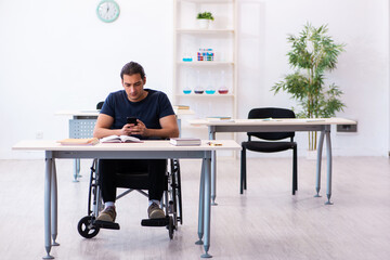 Young male student in wheel-chair preparing for exams