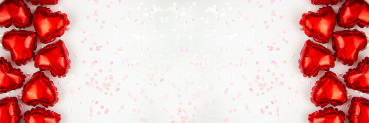 Heart-shaped foil balloons and shiny confetti on a light background. Valentine's day holiday concept. Flat lay.