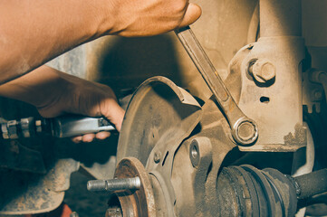 Car Mechanic or Auto Mechanic Loosen Shock Absorber Bolt and Nut by Wrench and Wind Block from...