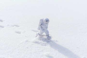 Statuette of an astronaut confidently explores alien planet's surface. Cold planet covered with snow.