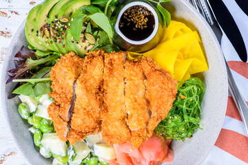 A serving of Chicken Poke Bowl with Tonkatsu chicken, pickled vegetables, avocado slices, cucumber...