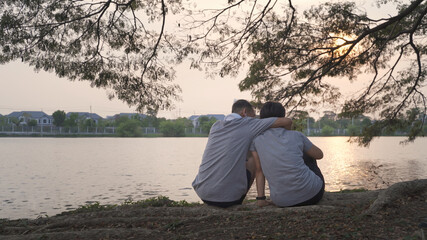 happy senior couple sitting near lake view hugging at park