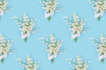 Creative pattern with spring flowers white lilies of the valley on blue. Seasonal floral design.