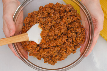Mix of fried ground beef and marinara sauce in a bowl, and lasagna noodles close up on kitchen...