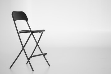 High folding chair. Black color. Light background.