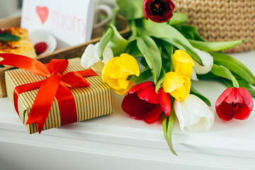 Beautiful bouguet of flowers tulips, package gift box, healthy breakfast with cup of coffee