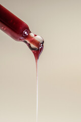 A drop of red serum drops from the pipette